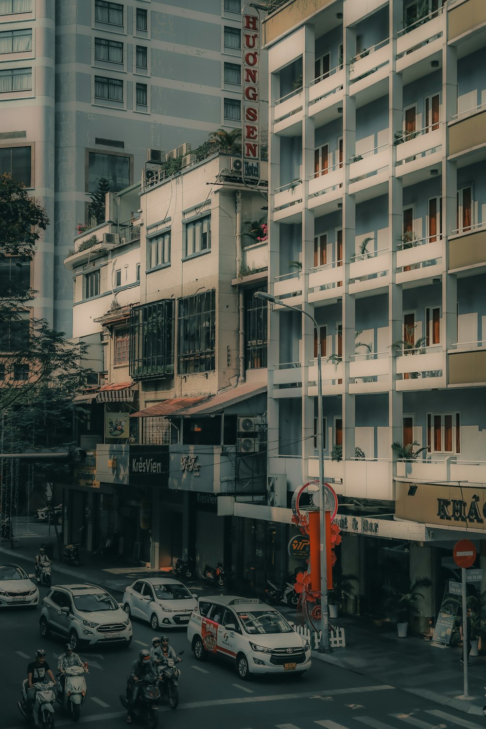 a group of cars driving down a street next to tall buildings