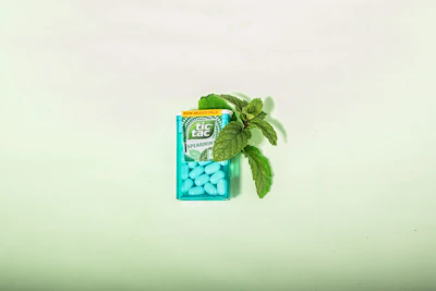 Close-up of a hand holding a vibrant energy gum pack with fresh mint leaves around