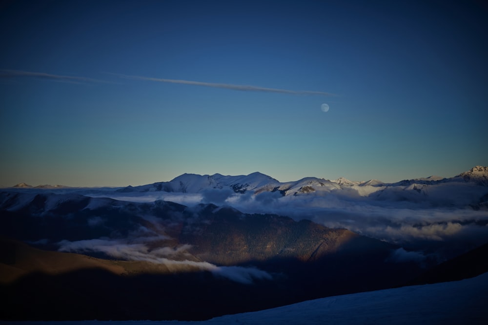 a view of a mountain range with a moon in the sky