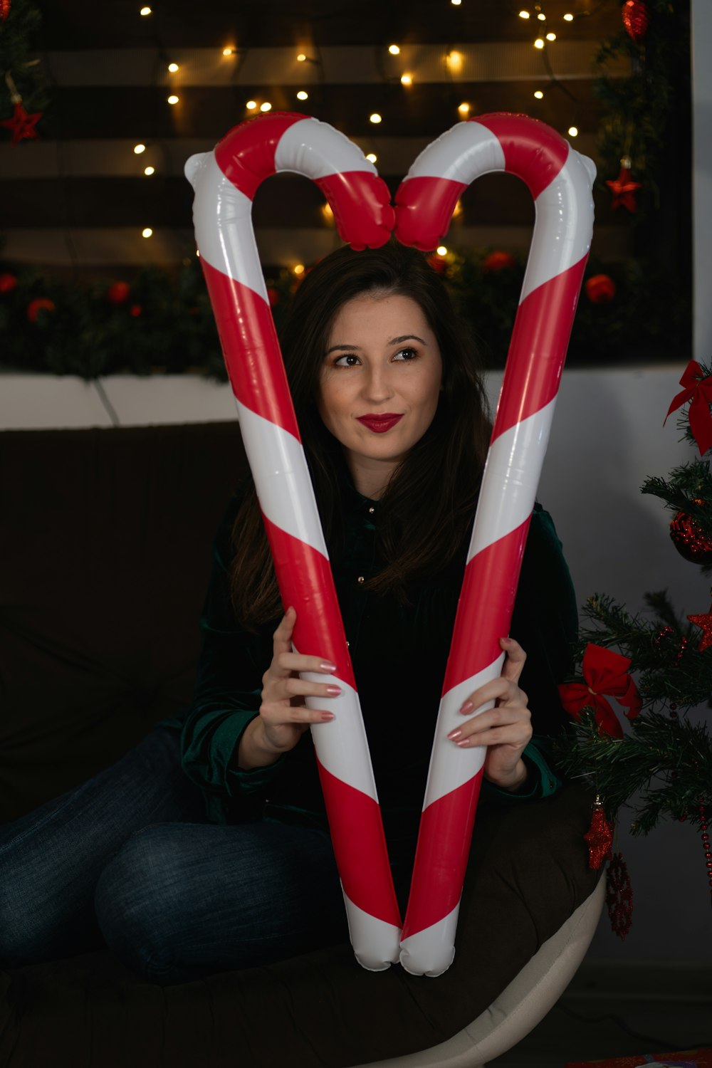 a woman sitting on a couch holding two giant candy canes