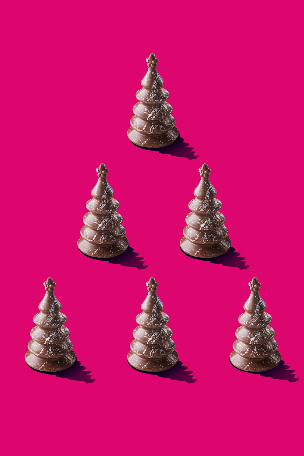 a group of small christmas trees on a pink background