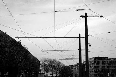 Technician inspecting overhead railway cables on a clear day with modern city tram tracks.