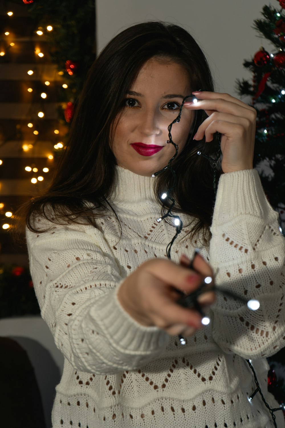 a woman holding a cell phone in front of a christmas tree