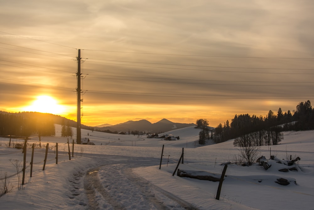 the sun is setting over a snowy landscape