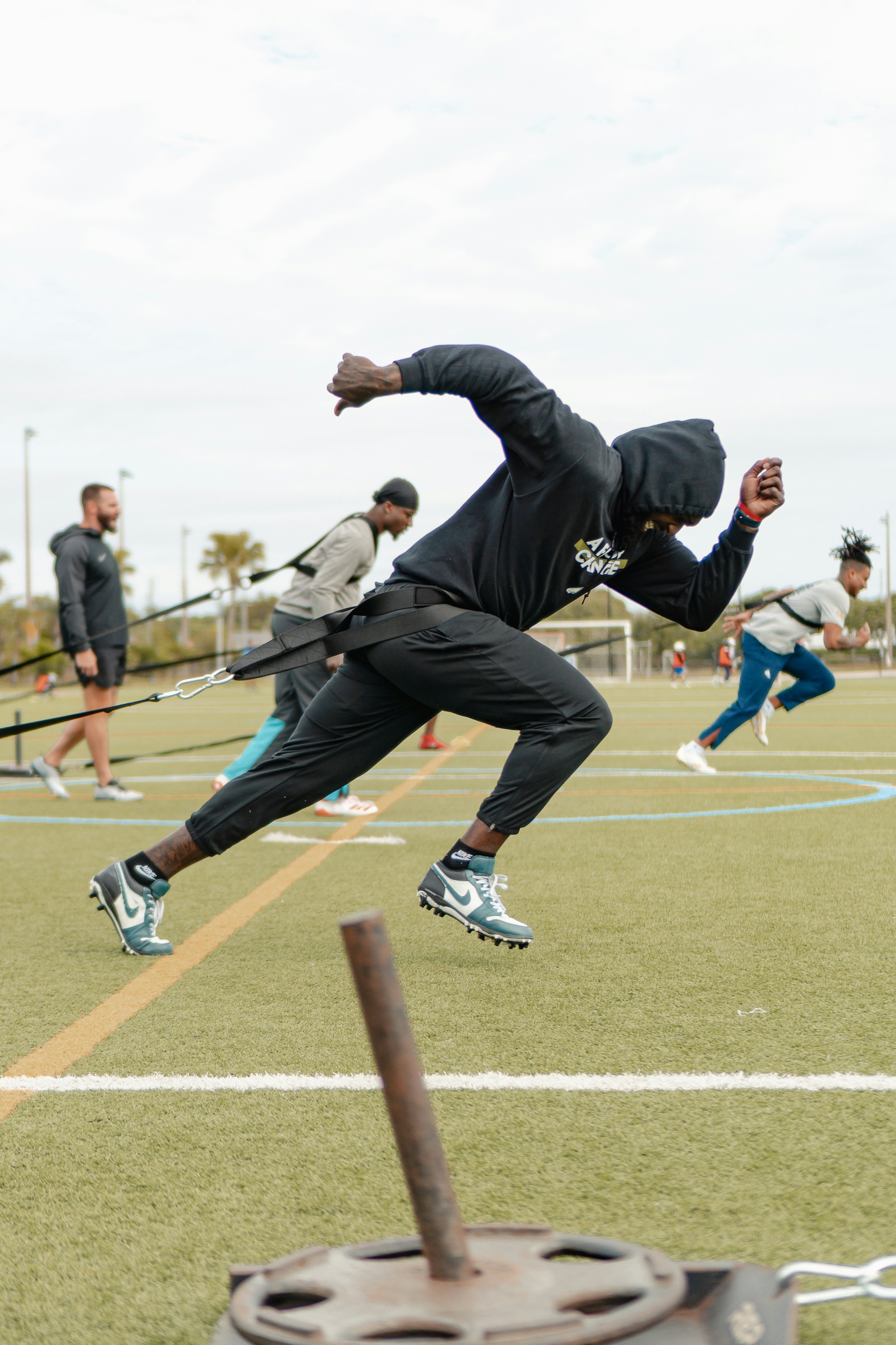 Athletes in community training session, dim natural light, deep earth tones, grounded athletic energy