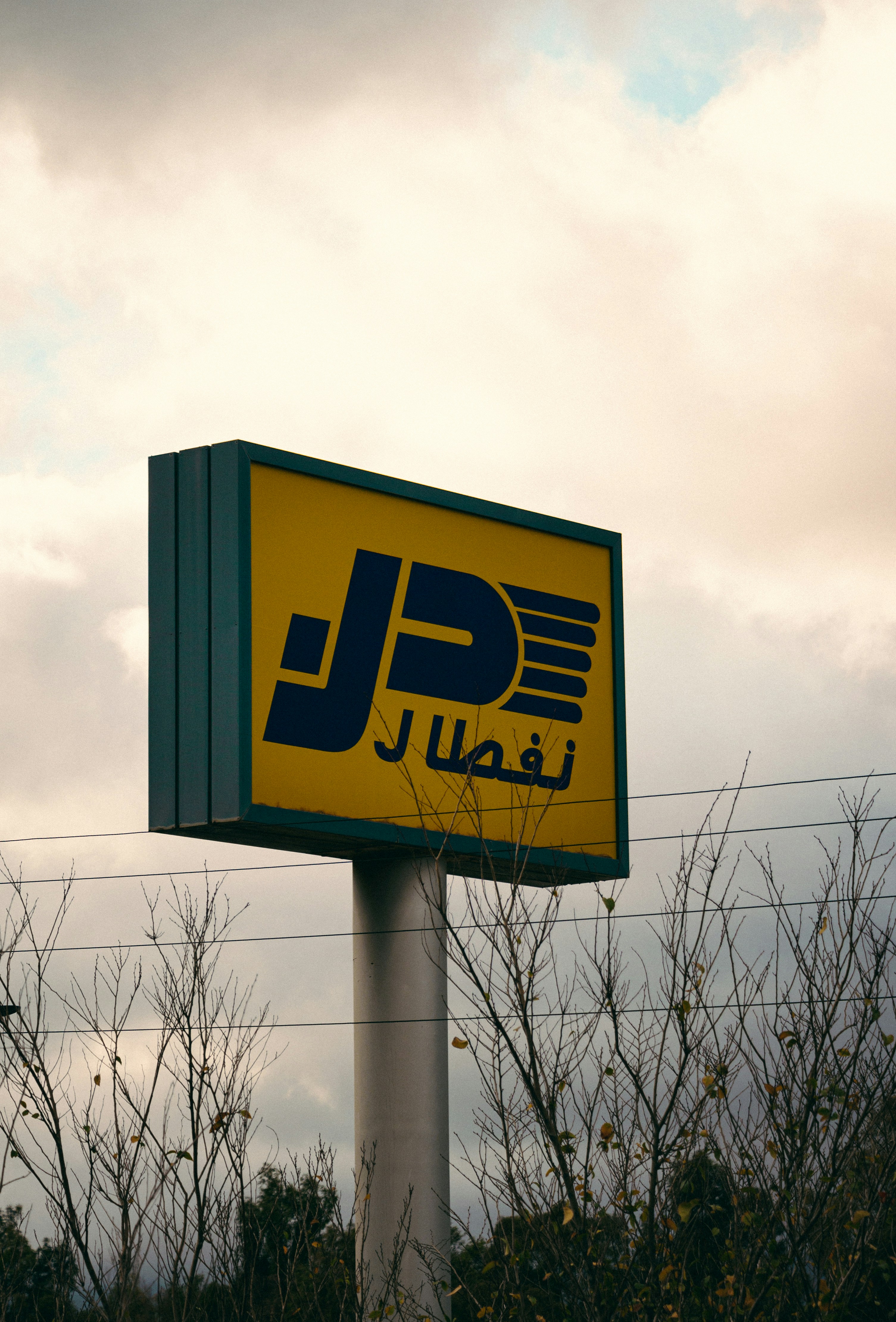 a yellow and green sign in front of a cloudy sky