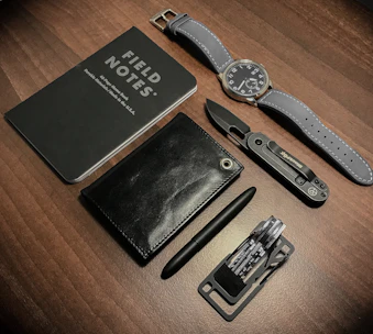 A rugged EDC kit laid out neatly, featuring a knife, multitool, and flashlight.