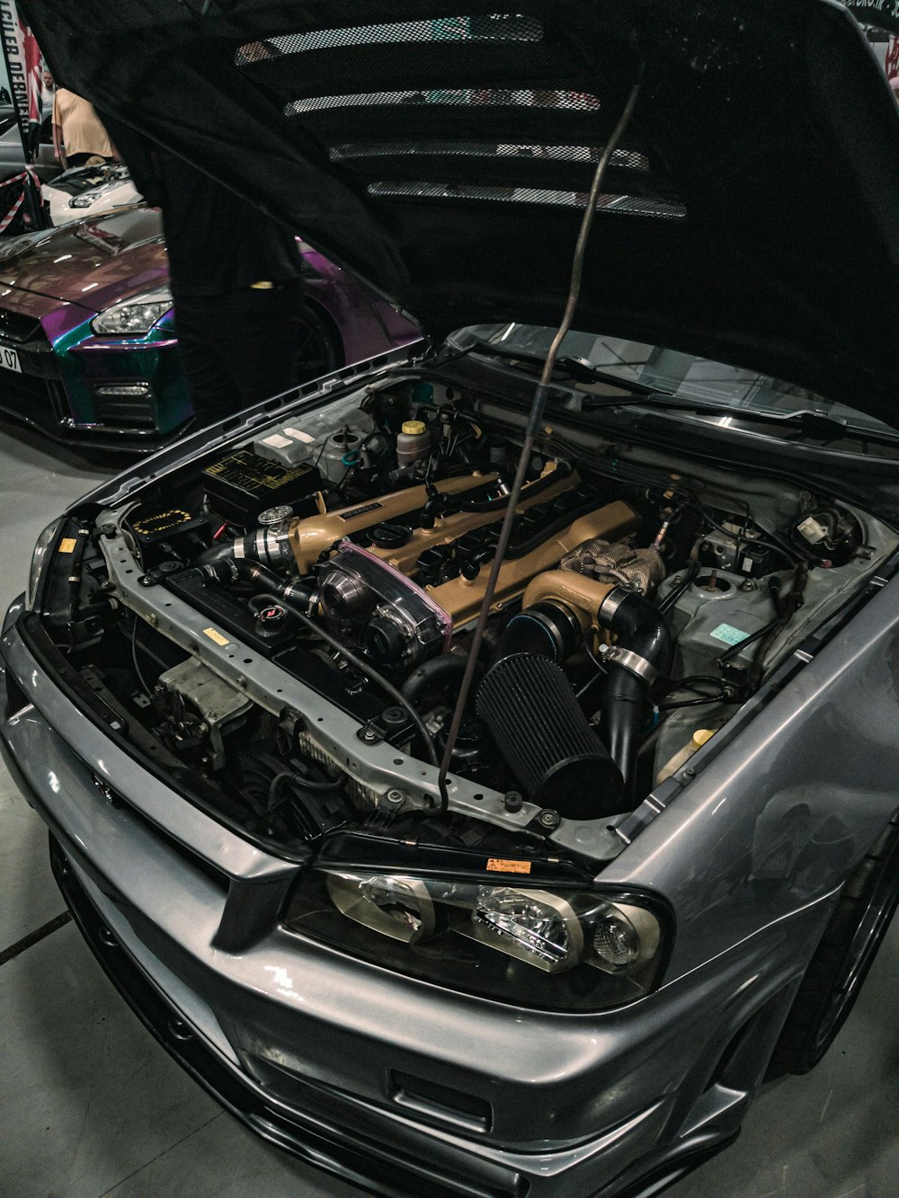 a silver car with its hood open in a garage