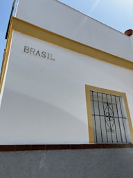 a white building with a yellow window and a wrought iron door