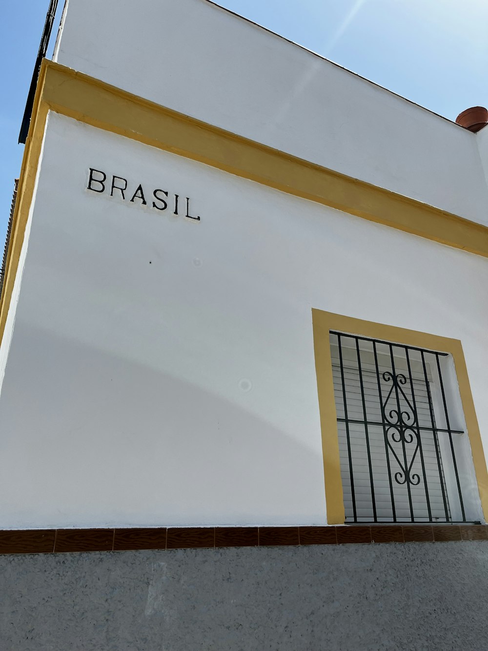 a white building with a yellow window and a wrought iron door