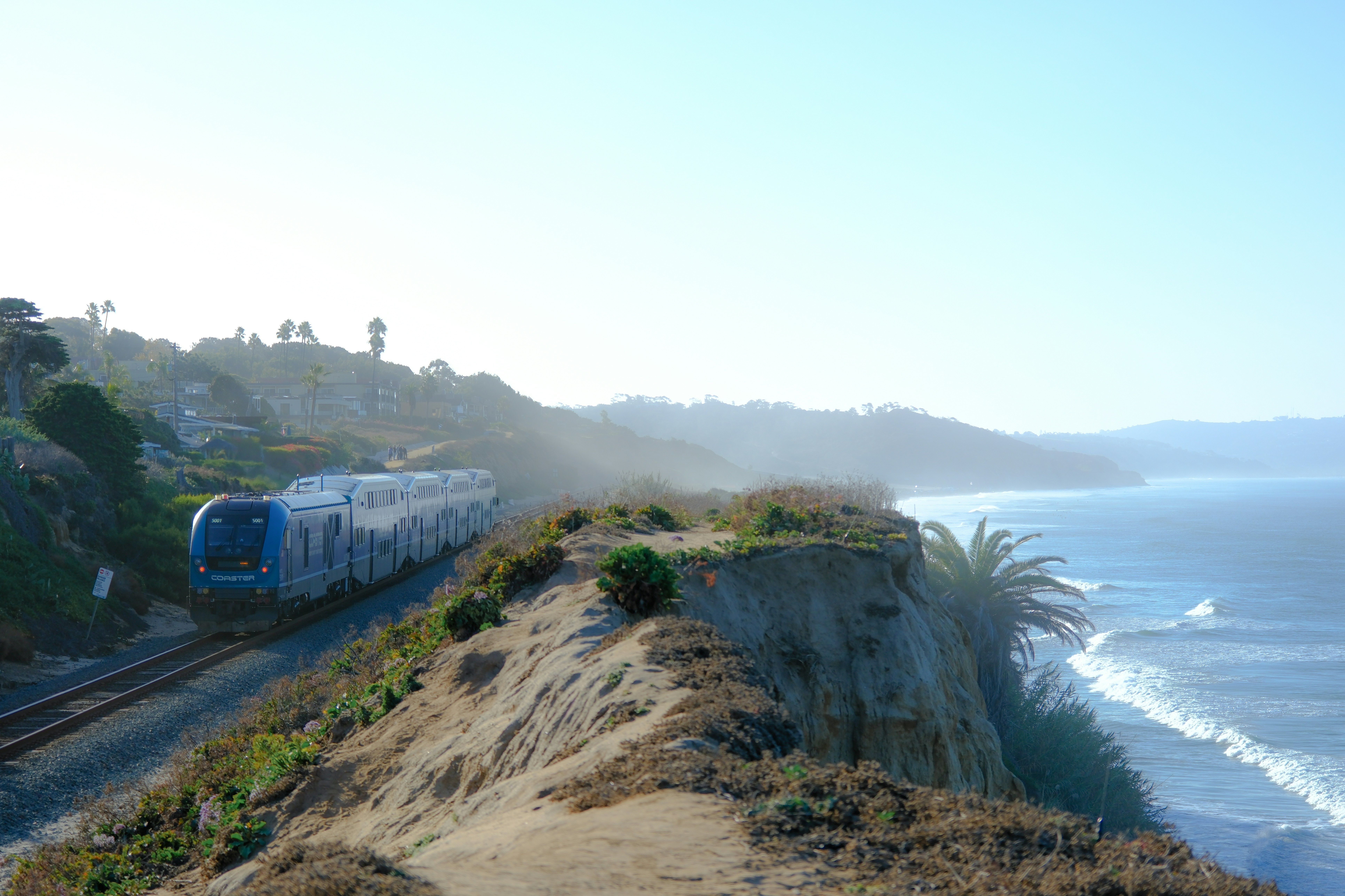 A train traveling down tracks next to the ocean photo – Free Del mar ...