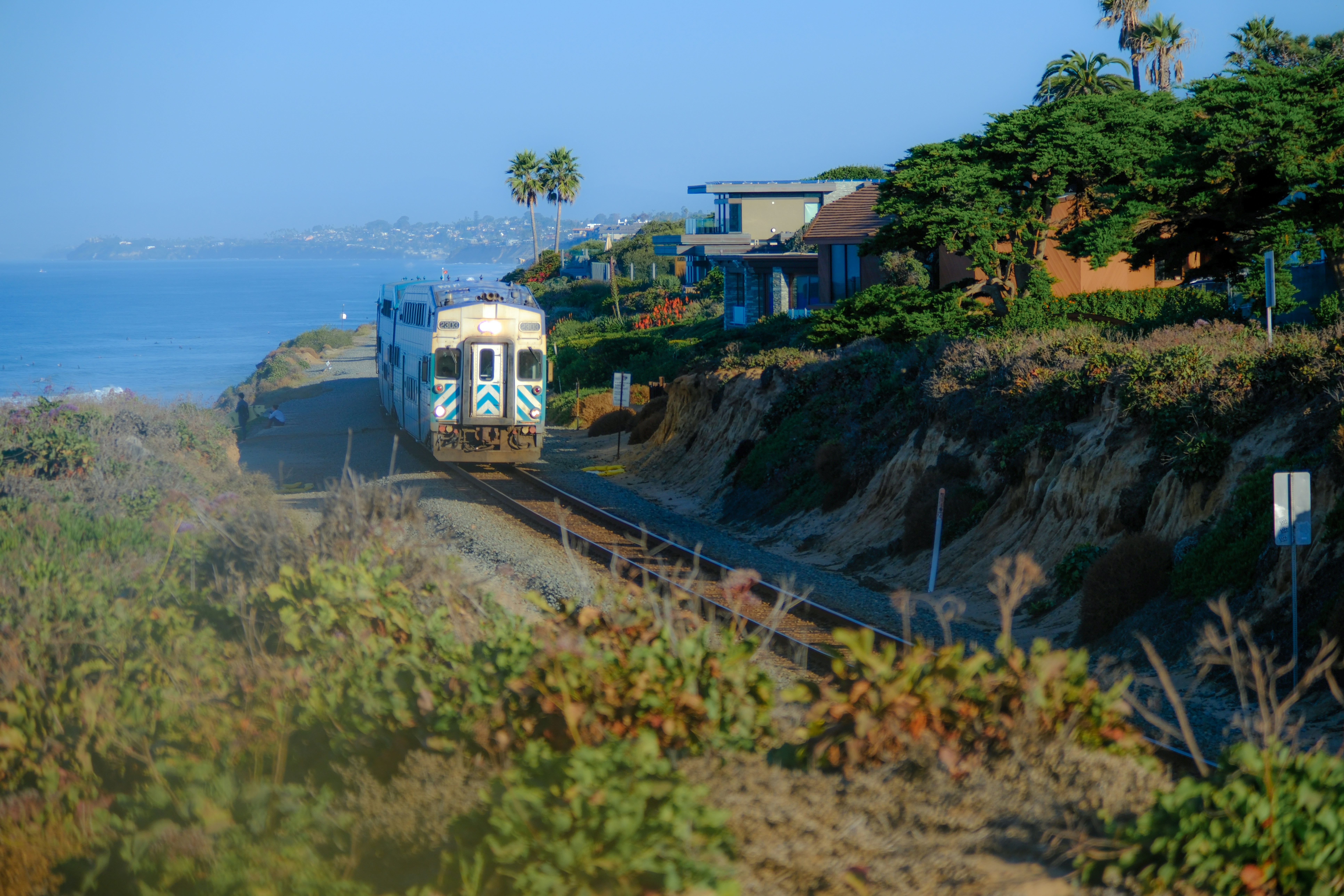 a train traveling down tracks next to a lush green hillside, 