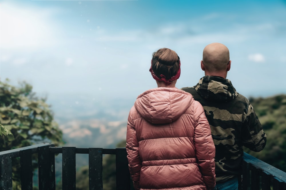 a man and a woman sitting on a bench looking out over a valley