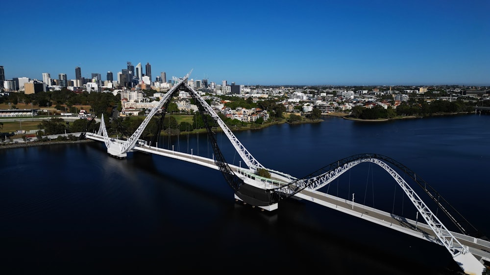 an aerial view of a bridge spanning a river with a city in the background