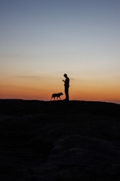 A happy pet owner using the Silpet app on a smartphone while their dog waits nearby.