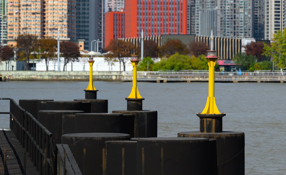 a row of yellow poles sitting next to a body of water