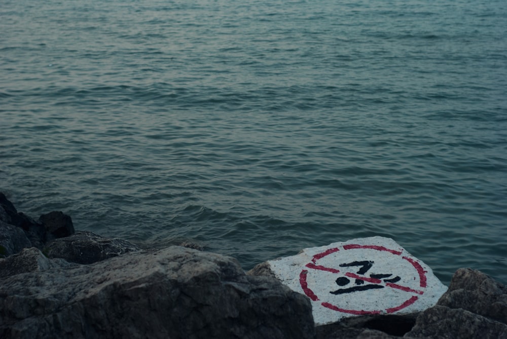 a sign that is on the rocks by the water