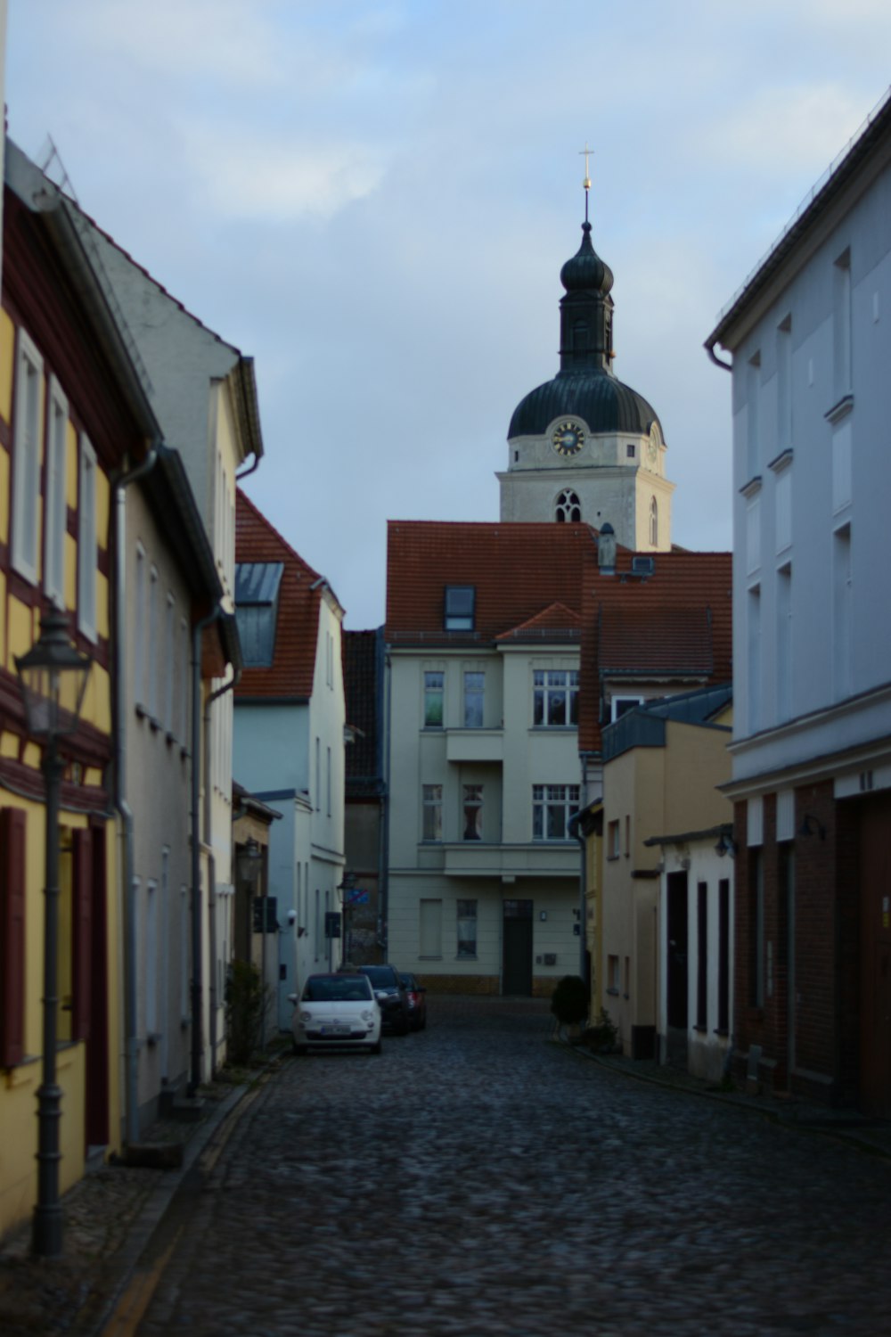 eine Kopfsteinpflasterstraße mit einem Kirchturm im Hintergrund