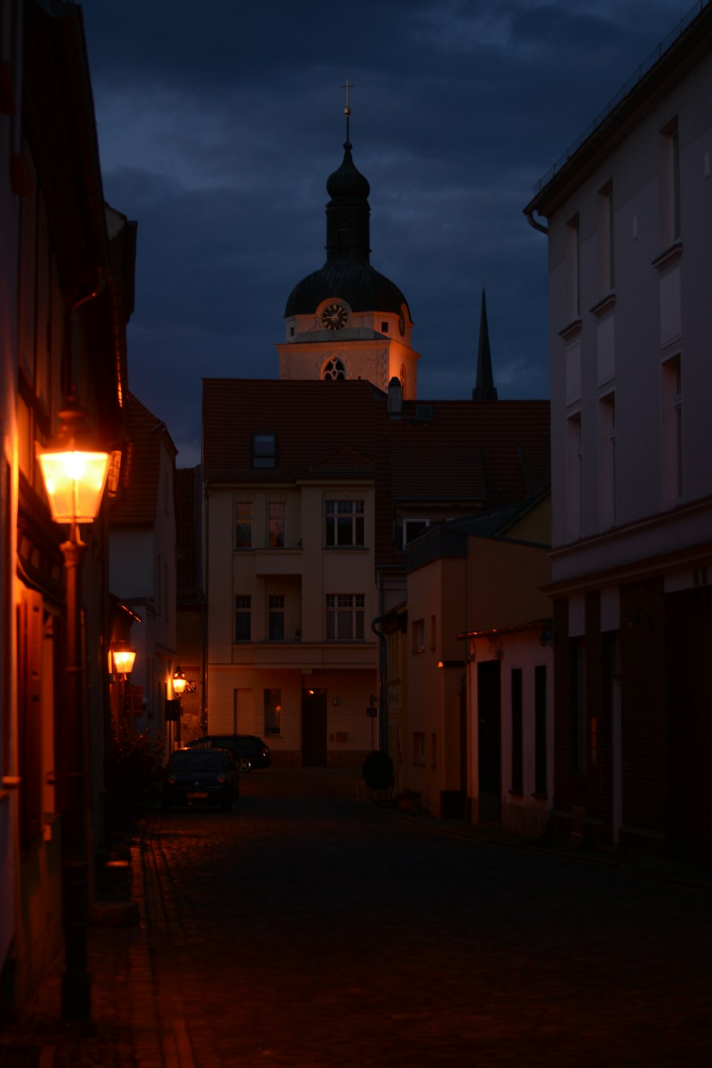 una calle oscura con una torre de reloj al fondo