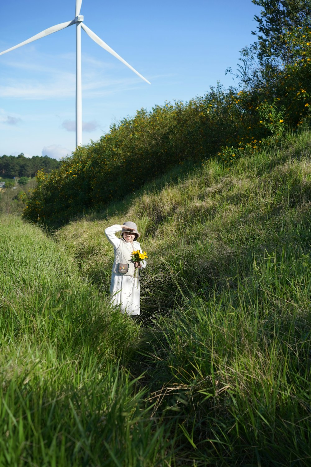 a woman standing in a field next to a wind turbine