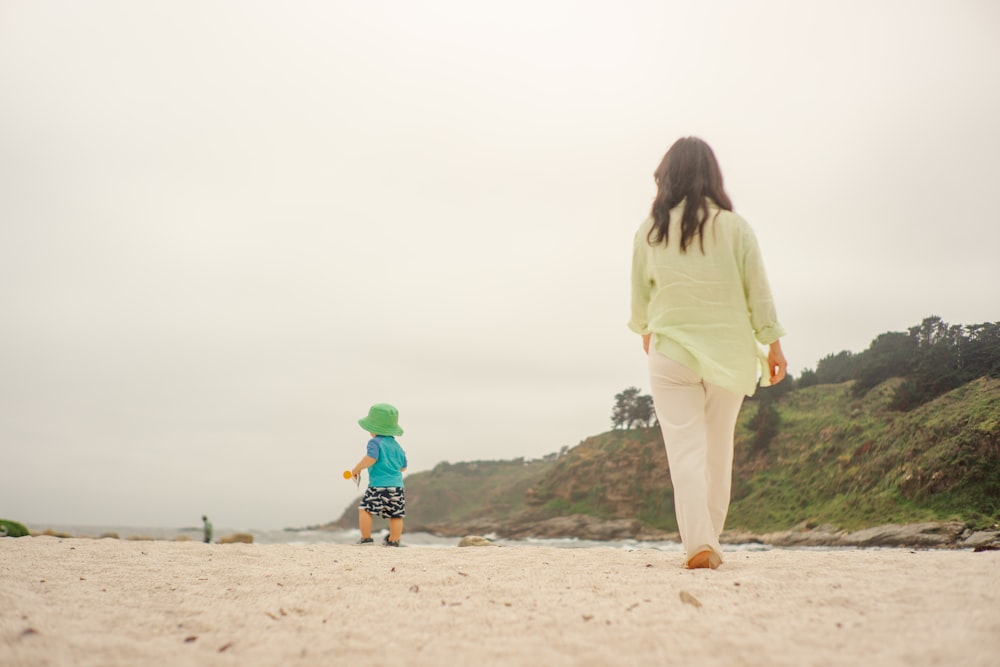 a woman and a child walking on a beach