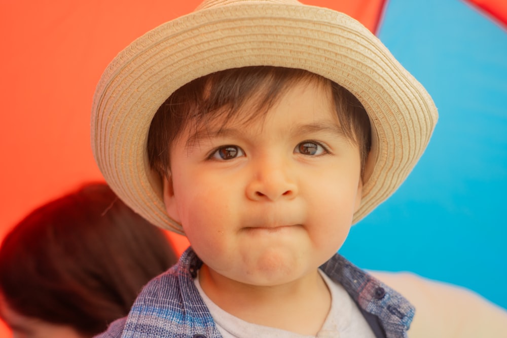 a little boy wearing a hat and making a funny face