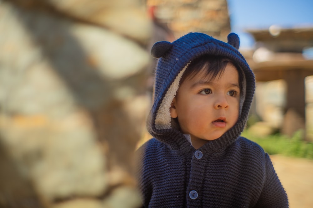 a small child wearing a blue bear sweater