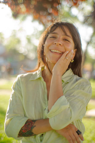 A person applying SPF cream on their arm while smiling outdoors.