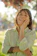 Smiling woman outdoors with a subtle circular light blue patch on her wrist, sunlight filtering softly.