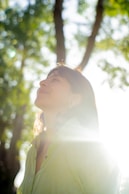 A focused person standing strong with soft sunlight filtering through trees, embodying presence and personal power.