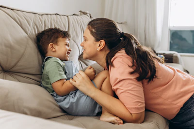 A mother and child sharing a laugh while doing a matching activity on the living room floor.