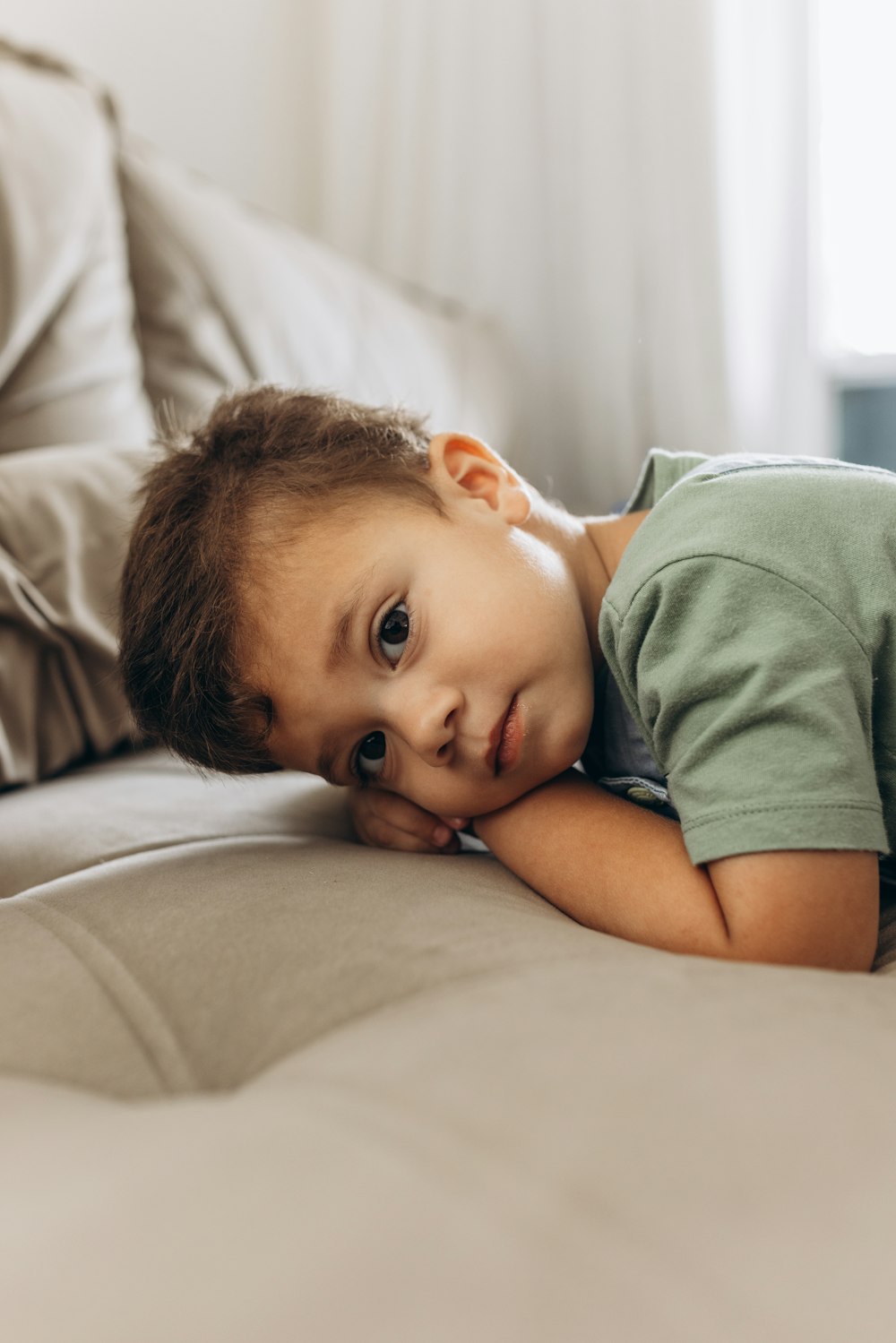 a young boy laying on top of a bed