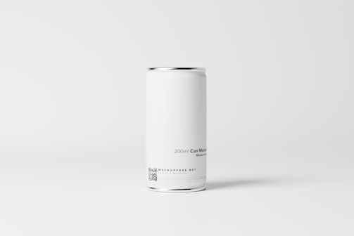 A plain white aluminum can is placed against a minimalistic, light gray background. The can has a sleek and smooth surface with text indicating a capacity of 200ml, and includes a small QR code and website information near the bottom.