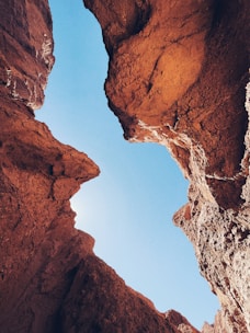 A panoramic view of a narrow canyon with turquoise pools and rugged cliffs under a bright sky.