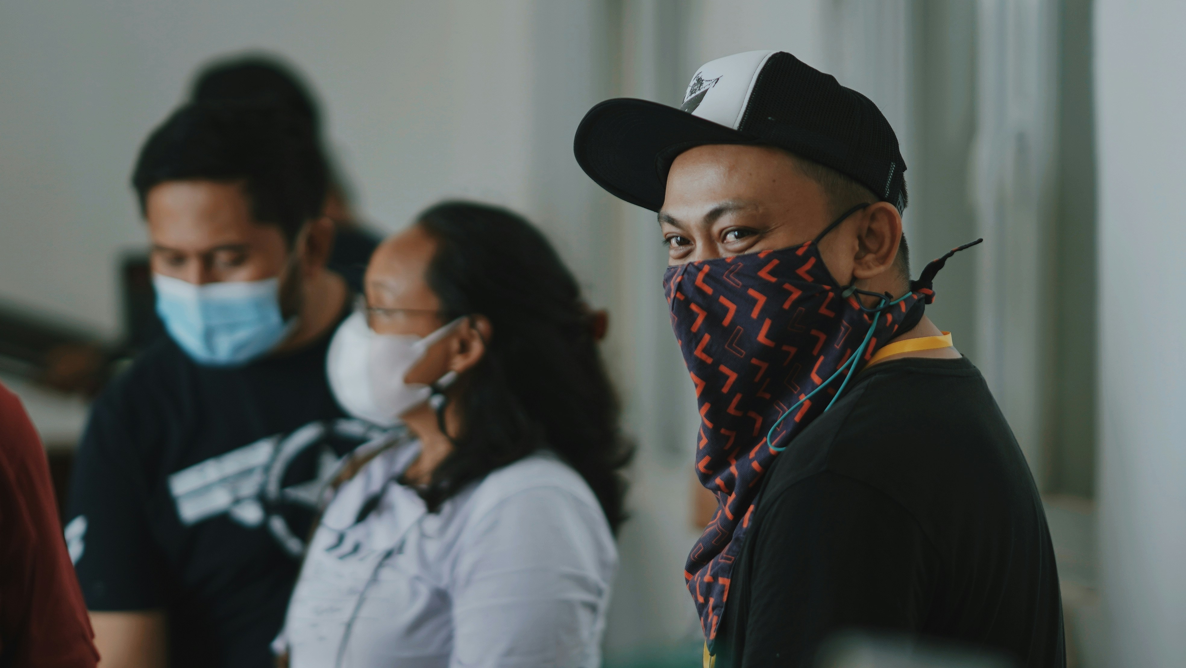 sekelompok orang berdiri di sekitar satu sama lain mengenakan masker wajah