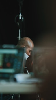 A recruiter thoughtfully browsing masked candidate profiles on an office monitor.