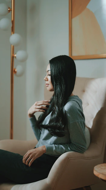 a woman sitting in a chair with her hands on her chest