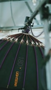A large, professional lighting setup is depicted. The image focuses on a dome-shaped softbox with a series of small lights attached to its ribs. The softbox has a dark surface with purple accents and is branded with the text '180 B2 Pro Lightstar'. It is suspended from a metal structure, suggesting a studio environment.