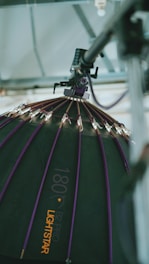 A large, professional lighting setup is depicted. The image focuses on a dome-shaped softbox with a series of small lights attached to its ribs. The softbox has a dark surface with purple accents and is branded with the text '180 B2 Pro Lightstar'. It is suspended from a metal structure, suggesting a studio environment.