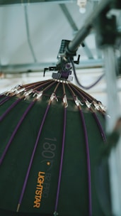 A large, professional lighting setup is depicted. The image focuses on a dome-shaped softbox with a series of small lights attached to its ribs. The softbox has a dark surface with purple accents and is branded with the text '180 B2 Pro Lightstar'. It is suspended from a metal structure, suggesting a studio environment.