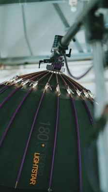 A large, professional lighting setup is depicted. The image focuses on a dome-shaped softbox with a series of small lights attached to its ribs. The softbox has a dark surface with purple accents and is branded with the text '180 B2 Pro Lightstar'. It is suspended from a metal structure, suggesting a studio environment.