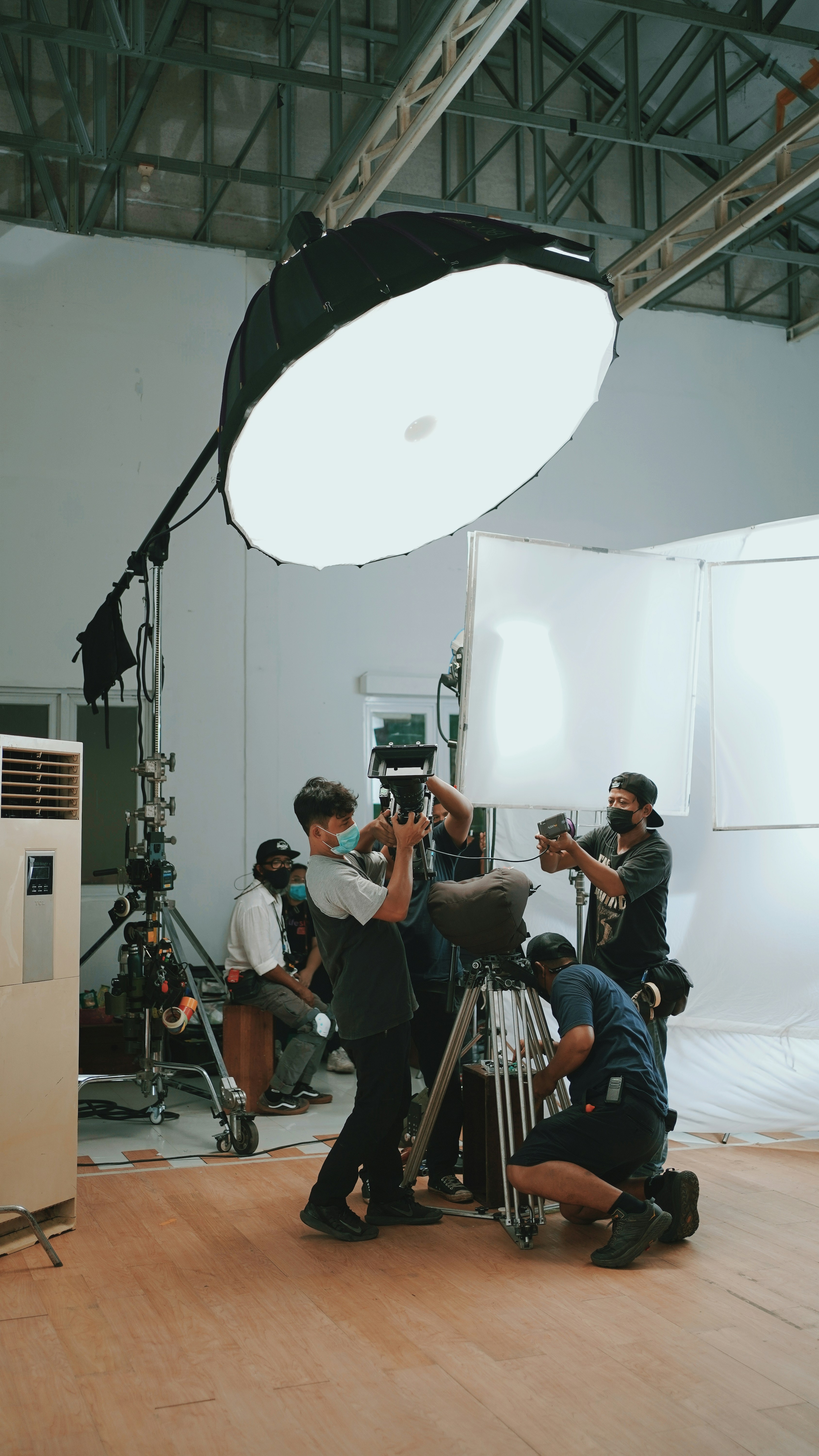 A group of people standing around a camera photo – Free Man Image on ...
