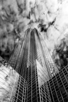 A sleek black-and-white drone shot capturing the sharp angles of a modern tower at dusk.