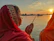 A serene photo of a pilgrim performing pinddaan by the Falgu river at sunset, with the Vishnupad temple softly glowing in the background.