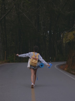 a person walking down a road with a backpack and a frisbee