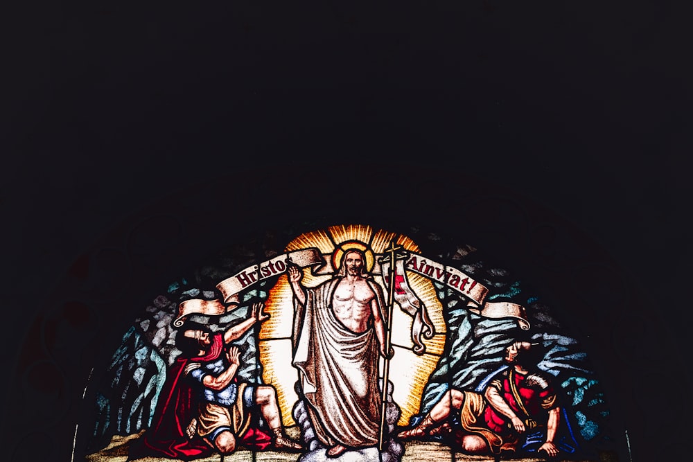a stained glass window with a statue of jesus