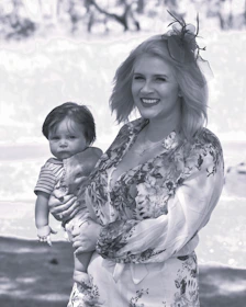 A smiling mother wearing a busui-friendly daster, holding her baby comfortably.
