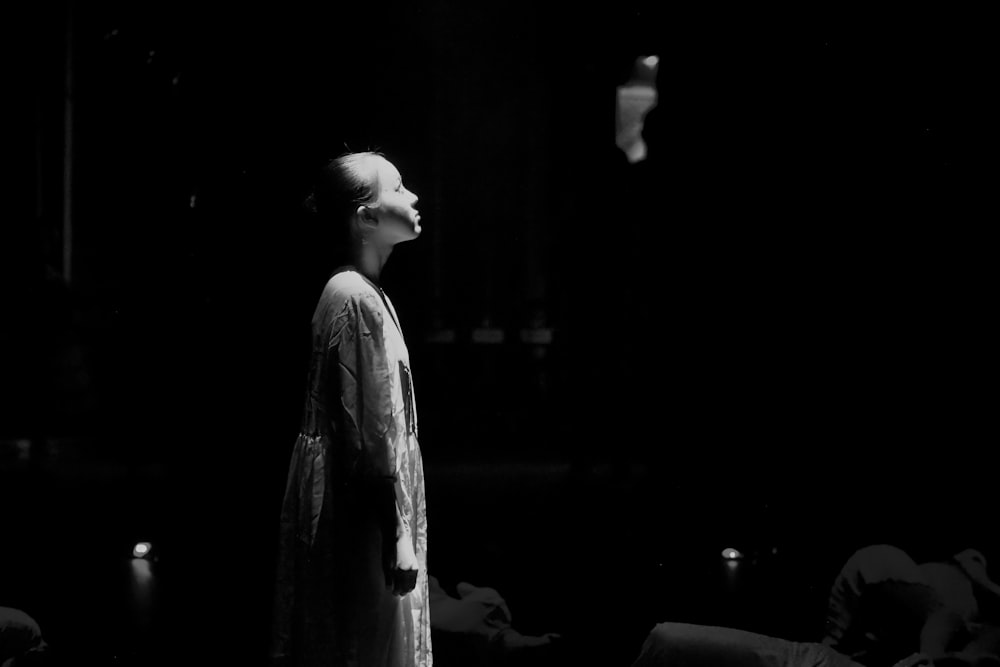 a black and white photo of a woman standing in the dark