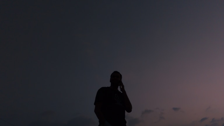 A silhouette of a lone figure against a dusky sky with deep blue tones.