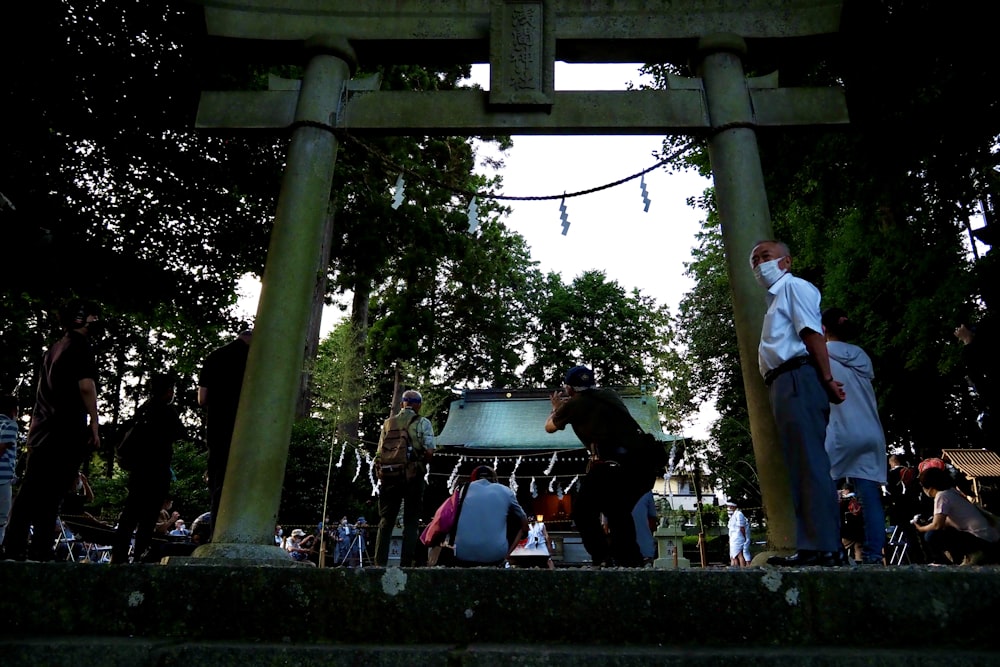 a group of people standing under a tall wooden structure